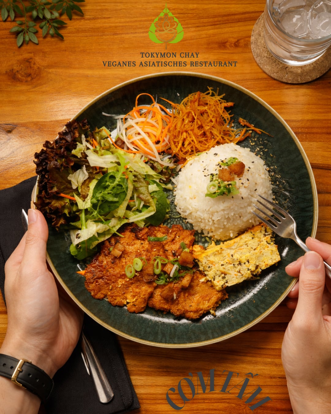 Veganer Teller mit Reis, Salat, Gemüse, knusprigen Stücken und Tofu auf einem Holztisch